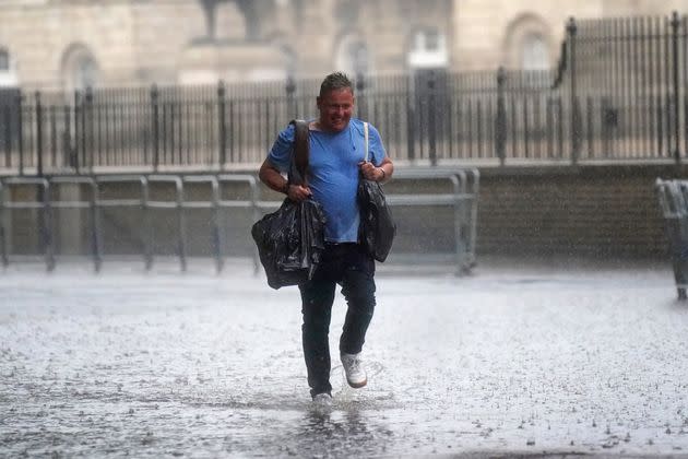 A man walks through water in Horse Guards Road on July 25 (Photo: Victoria Jones - PA Images via Getty Images)