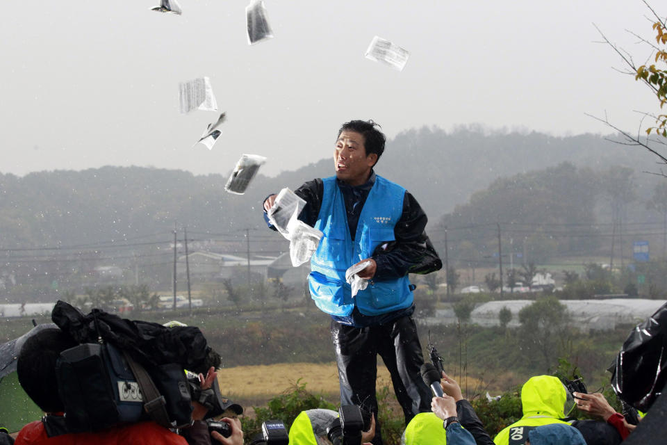 FILE - In this Oct. 22, 2012, file photo, Park Sang-hak, formerly a North Korean who fled to South Korea, hurls anti-North Korea leaflets as police block his planned rally on a road in Paju, near demilitarized zone, South Korea. Park said Tuesday, June 23, 2020 hundreds of thousands of leaflets had been launched by balloon across the border with North Korea overnight, after the North repeatedly warned it would retaliate against such actions. (AP Photo/Ahn Young-joon, File)