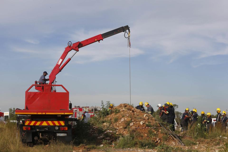 Rescue officials use a crane to remove debris as they work to rescue trapped suspected illegal miners from an abandoned gold shaft in Benoni