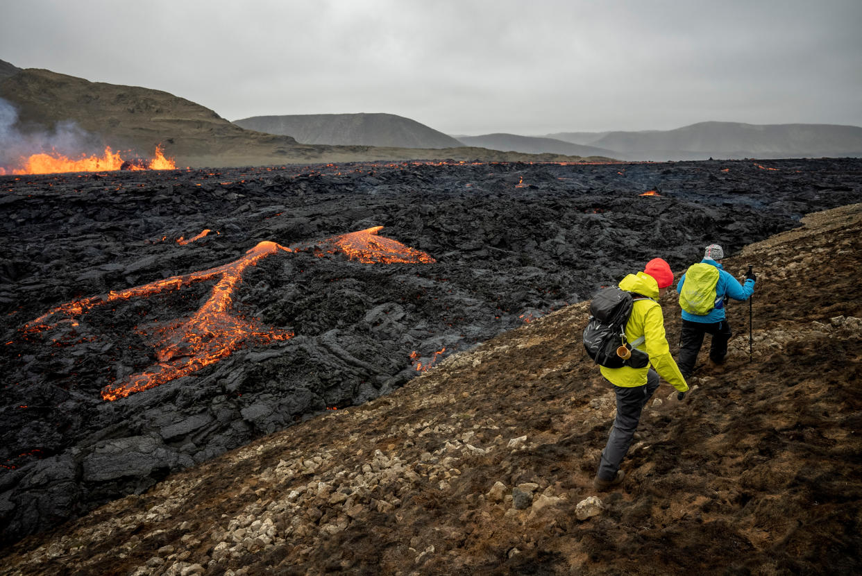 Hikers walks past Iceland's Fagradalsfjall volcano as it sputters lava from the uninhabited Meradalir Valley on the Reykjanes peninsula, about 20 miles from Reykjavik, Iceland August 5, 2022. REUTERS/Ken Cedeno