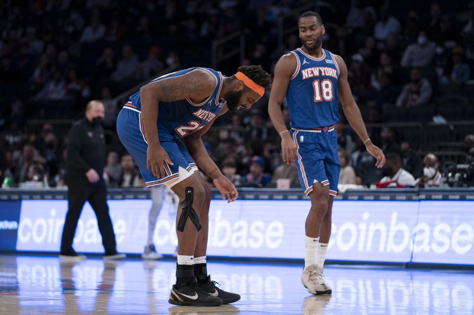 New York Knicks center Mitchell Robinson (23) doubles over in pain after an apparent injury alongside guard Alec Burks (18) during the second half of an NBA basketball game against the Los Angeles Clippers, Sunday, Jan. 23, 2022, in New York. (AP Photo/John Minchillo)