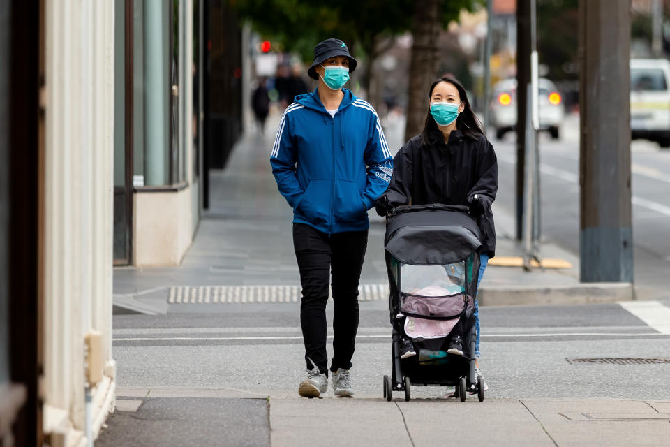 MELBOURNE, AUSTRALIA - APRIL 14: A couple walk down Chapel Street wearing masks during COVID 19 on 14 April, 2020 in Melbourne, Australia. (Photo by Speed Media/Icon Sportswire via Getty Images)