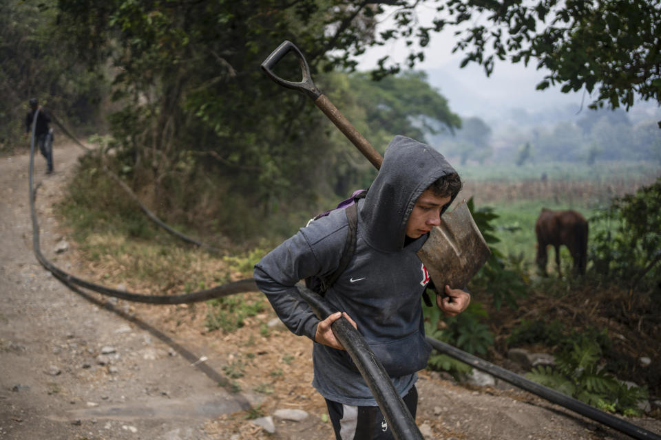 A villager pulls a hose to help contain a wildfire in Nogales, in the High Mountains area of Veracruz state, Mexico, Monday, March 25, 2024. (AP Photo/Felix Marquez)