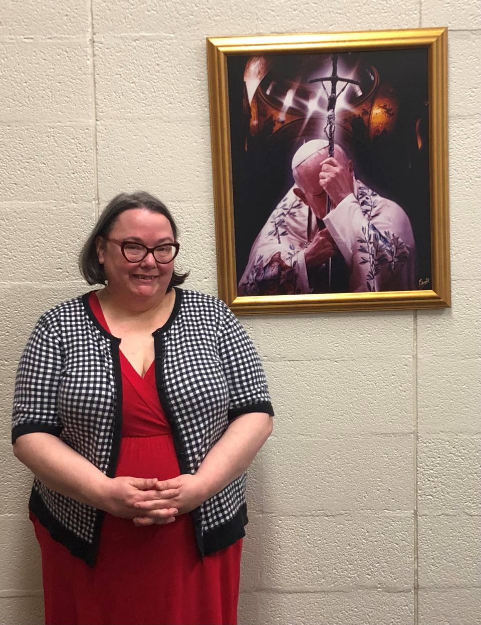 Martha Tidball, director of music and liturgy at Most Pure Heart of Mary Catholic Church in Shelby, stands in front of a portrait of Pope Saint John Paul II in the Parish.