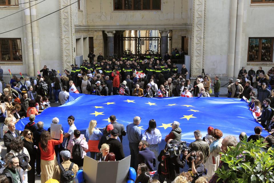 Protestors with a giant EU flag gather outside the parliament building in Tbilisi, Georgia, on Monday, April 15, 2024 to protest against the "the Russian law" as it is similar to a law that Russia uses to stigmatize independent news media and organizations seen as being at odds with the Kremlin. The governing party in the country of Georgia has submitted to parliament a draft law calling for media and non-commercial organizations to register as being under foreign influence if they receive more than 20% of their budget from abroad. (AP Photo/Shakh Aivazov)