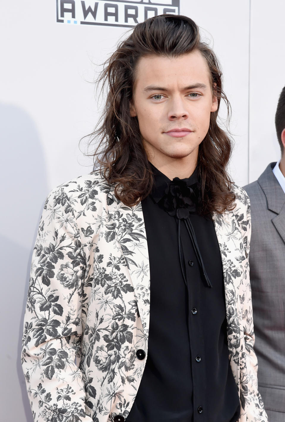 he's got long hair and he's wearing a floral blazer