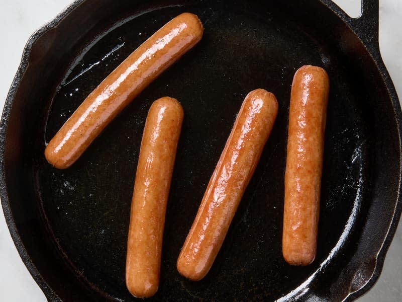 overhead photo of hot dogs cooked in a cast iron skillet
