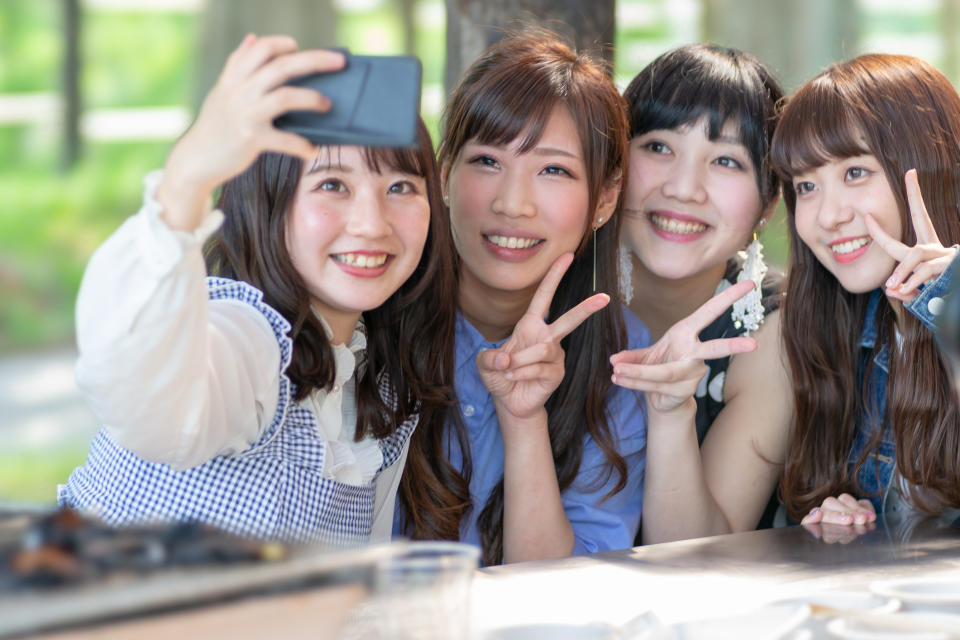 Four Japanese women take a selfie.