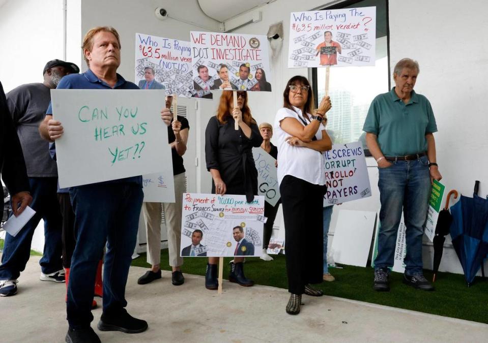 Coconut Grove resident Cecile Tavera-Webman carries a sign asking who is paying for the $63.5 million court verdict against City of Miami Commissioner Joe Carollo during a protest rally at Miami City Hall in Miami on Tuesday, June 6, 2023.