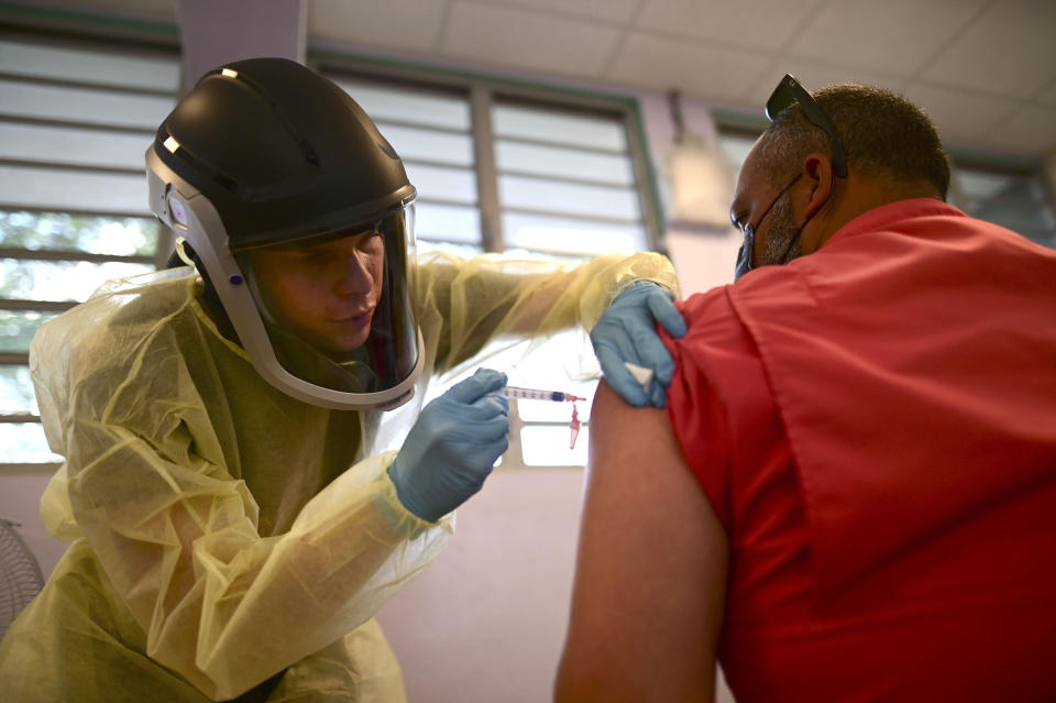 FILE - In this March 10, 2021 file photo, a healthcare worker injects a man with a dose of the Moderna COVID-19 vaccine during a mass vaccination campaign, at the Maria Simmons elementary school in Vieques, Puerto Rico. A spike in cases and hospitalizations has put medical experts at odds with the government, which is struggling to protect people’s health while also trying to prevent an economic implosion on an island battered by hurricanes, earthquakes and a prolonged financial crisis. (AP Photo/Carlos Giusti, File)