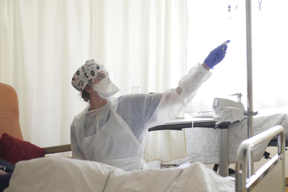 FILE- In this March 19, 2021, file photo, a nurse tends to a patient affected by COVID-19 virus in the ICU unit at the Ambroise Pare clinic in Neuilly-sur-Seine, near Paris. France's president say he has nothing to be sorry about for refusing to impose a third virus lockdown earlier this year, even though his country is now facing surging infections that are straining hospitals and more than 1,000 people with the virus are dying every week. (AP Photo/Thibault Camus, File)