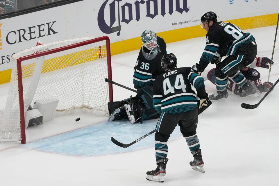 San Jose Sharks goaltender Kaapo Kahkonen (36), defenseman Marc-Edouard Vlasic (44) and defenseman Jan Rutta (84) watch as the puck approaches the net on a goal by Columbus Blue Jackets center Boone Jenner, right, during the third period of an NHL hockey game in San Jose, Calif., Saturday, Feb. 17, 2024. (AP Photo/Jeff Chiu)