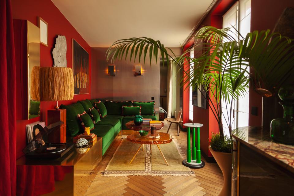 The main living space features pieces from different styles and eras, such as the sofa designed by Hugo with a Pierre Frey velvet fabric, sconces by Gio Ponti, a coffee table by Hélène de Saint Lager, a Moroccan rug, a Memphis-style green table in marble from the ’80s, and a surrealist painting by Andrée Pollier.