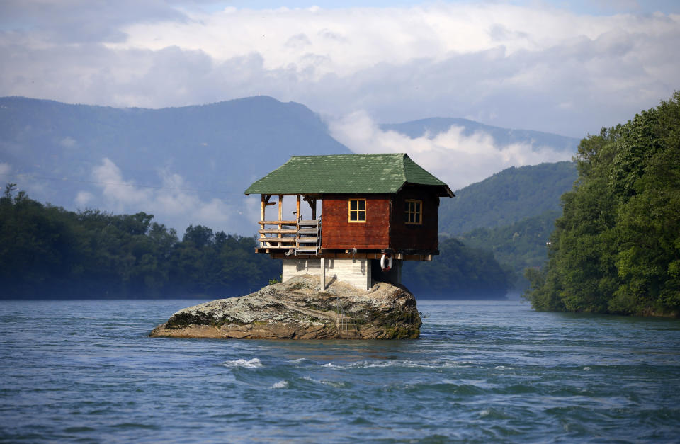 Un hombre maneja un bote cerca de una casa construida encima de una roca en el río Drina, en la ciudad serbia de Bajina Basta, a 160 kilómetros de Belgrado, la capital. Este pequeño refugio fue construido en 1968 por jóvenes de la zona, entre los que se incluía uno de los actuales propietarios. (REUTERS/Marko Djurica)