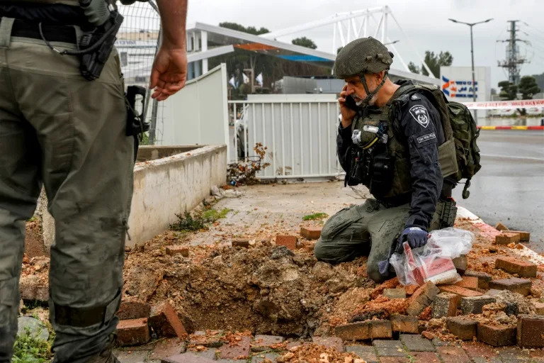 An Israeli policeman inspects the impact crater left by a rocket fired from southern Lebanon in the northern city of Safed (Jalaa MAREY)