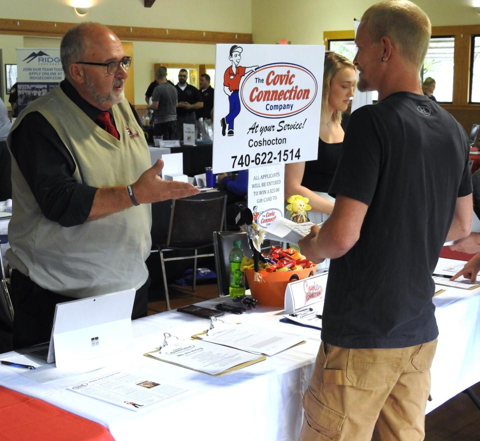 Chris Covic of Covic Connection talks with attendee of the Ohio Means Jobs of Coshocton County annual employment expo at the Lake Park Pavilion.