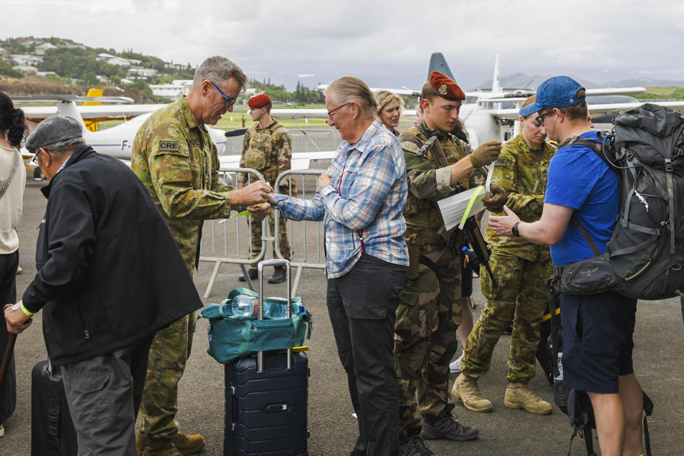 In this photo provided by the Australian Department of Defence, Australian defence force staff members assist Australian and other tourists as they prepare to depart from Magenta Airport in Noumea, New Caledonia, Tuesday, May 21, 2024. Australia and New Zealand have sent airplanes to New Caledonia to begin bringing home stranded citizens from the violence-wracked French South Pacific territory. (LAC Adam Abela/Royal Australian Airfare via AP)