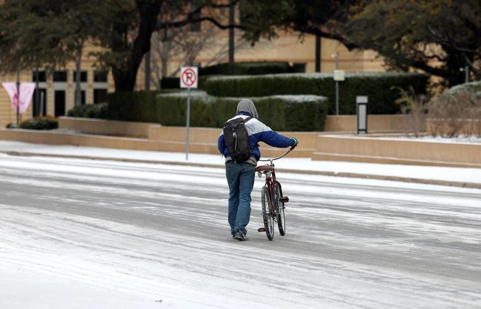 A man walks his bicycle across Commerce Street in downtown Fort Worth on Monday, January 15, 2024.