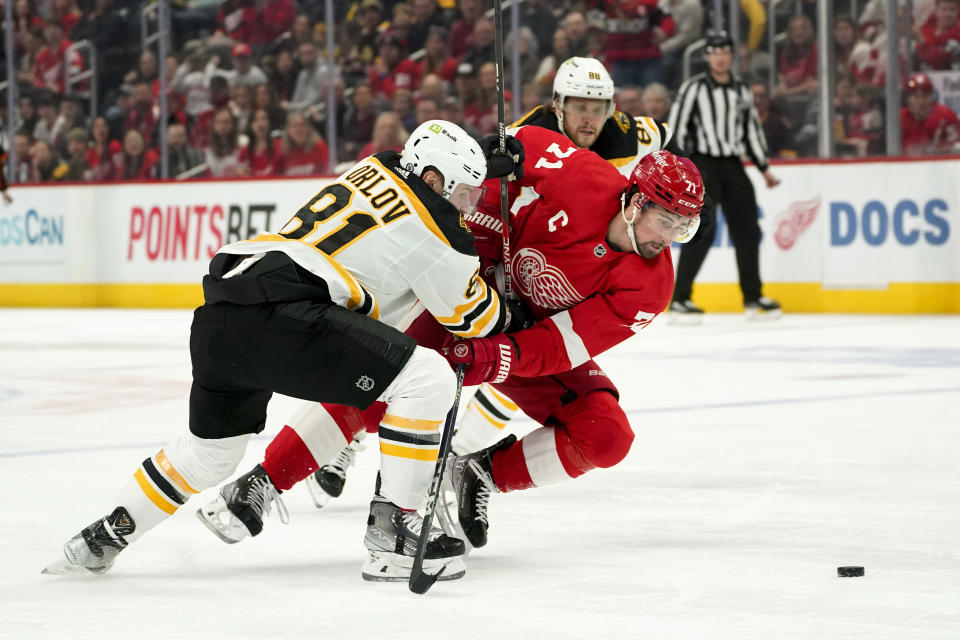 Boston Bruins defenseman Dmitry Orlov (81) knocks Detroit Red Wings center Dylan Larkin (71) off the puck in the first period of an NHL hockey game Sunday, March 12, 2023, in Detroit. (AP Photo/Paul Sancya)