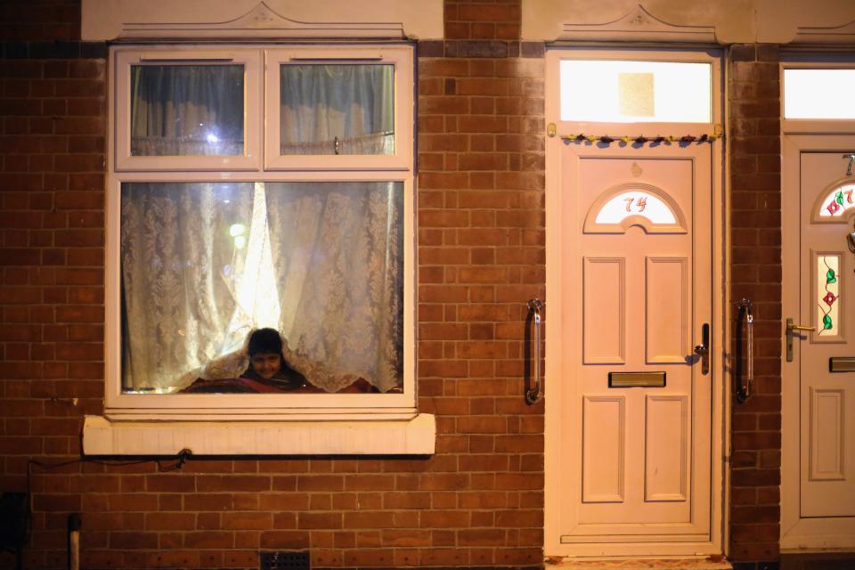 LEICESTER, UNITED KINGDOM - NOVEMBER 13: A young boy looks out from his home to watch fireworks during the Hindu festival of Diwali on November 13, 2012 in Leicester, United Kingdom. Up to 35,000 people attended the Diwali festival of light in Leicester's Golden Mile in the heart of the city's asian community. The festival is an opportunity for Hindus to honour Lakshmi, the goddess of wealth and other gods. Leicester's celebrations are one of the biggest in the world outside India. Sikhs and Jains also celebrate Diwali. (Photo by Christopher Furlong/Getty Images)