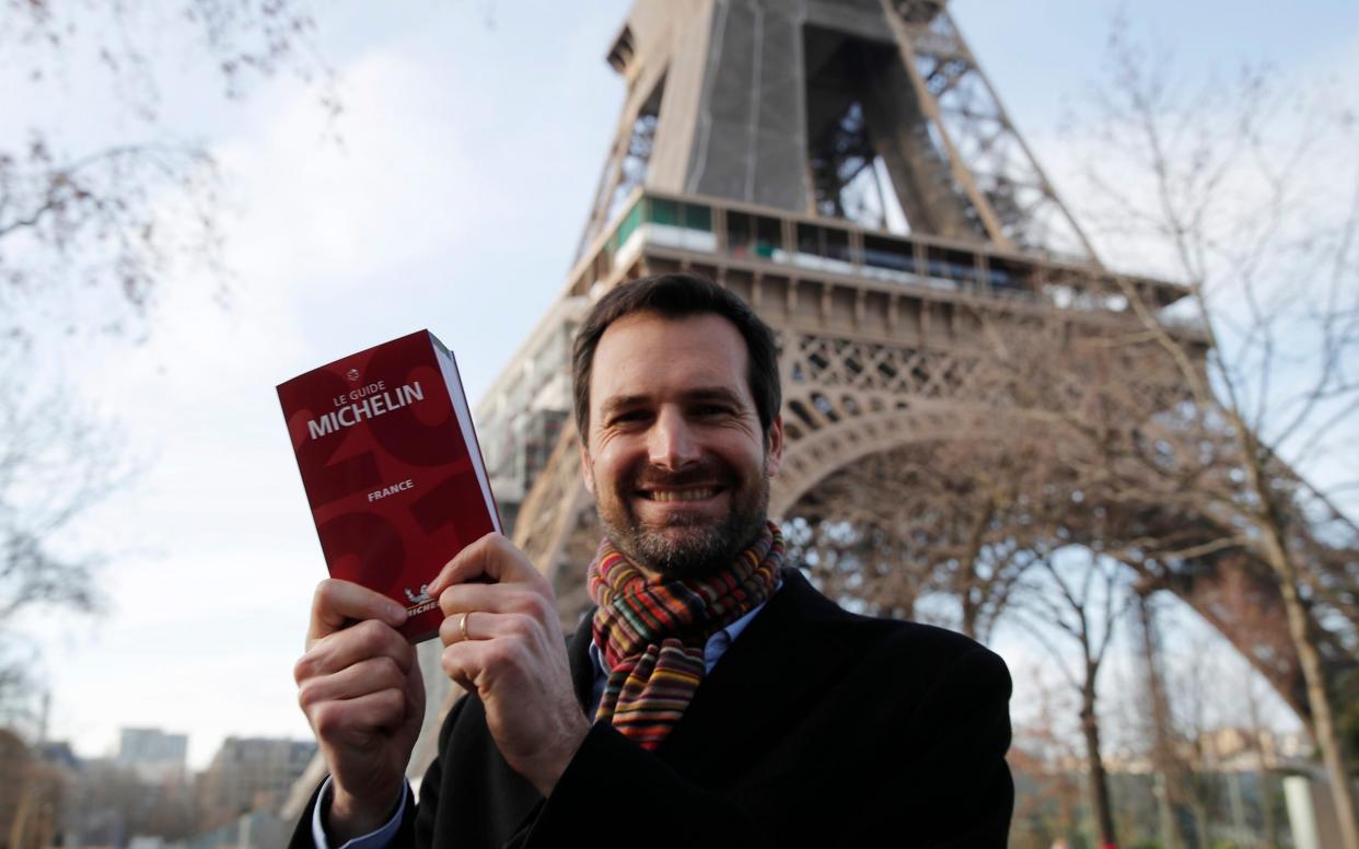 Gwendal Poullennec, head of Le Guide Michelin, poses outside the Eiffel Tower with the 2021 edition Monday, Jan. 18, 2021  - Francois Mori/AP