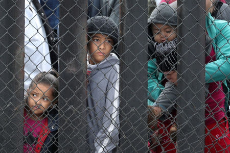 FILE PHOTO: Members of a migrant caravan from Central America and their supporters look through the U.S.-Mexico border wall at Border Field State Park before making an asylum request, in San Diego, California, U.S. April 29, 2018. REUTERS/Lucy Nicholson/File Photo