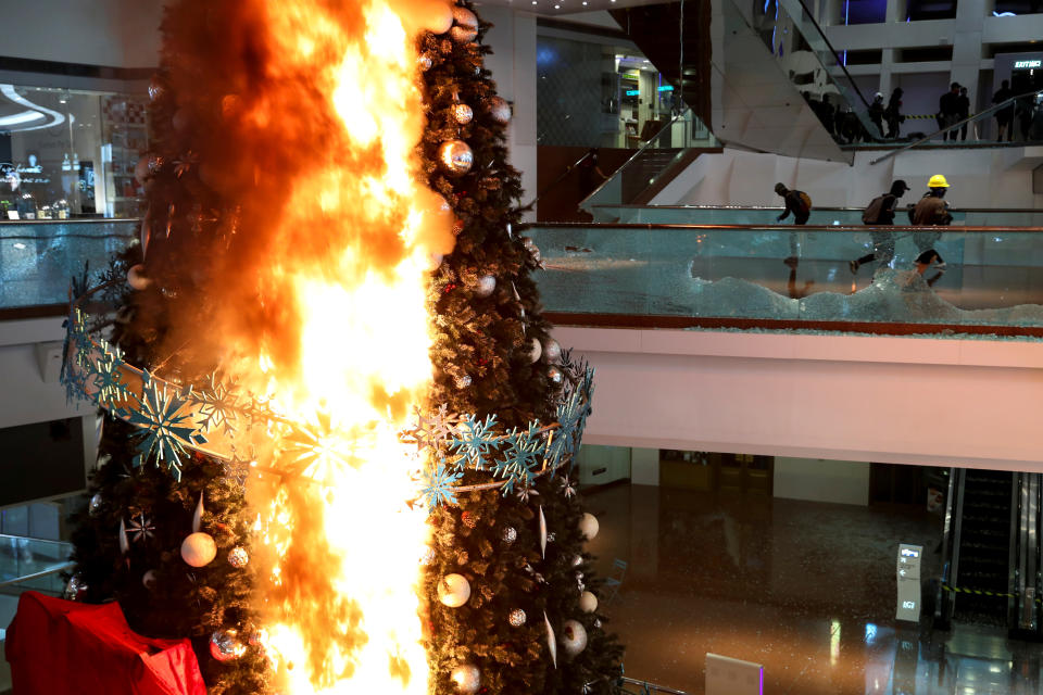 Protesters run next to a burning Christmas tree at Festival Walk mall in Kowloon Tong, Hong Kong, November 12, 2019. REUTERS/Athit Perawongmetha