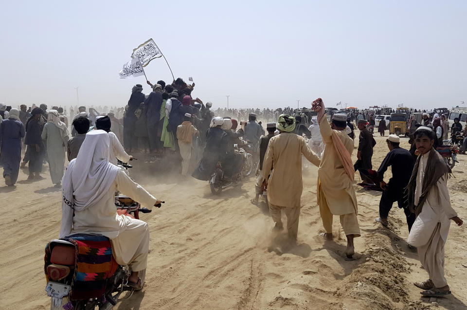 Supporters of the Taliban carry the Taliban's signature white flags in the Afghan-Pakistan border town of Chaman, Pakistan, Wednesday, July 14, 2021. The Taliban are pressing on with their surge in Afghanistan, saying Wednesday that they seized Spin Boldaka, a strategic border crossing with Pakistan — the latest in a series of key border post to come under their control in recent weeks. (AP Photo/Tariq Achkzai)