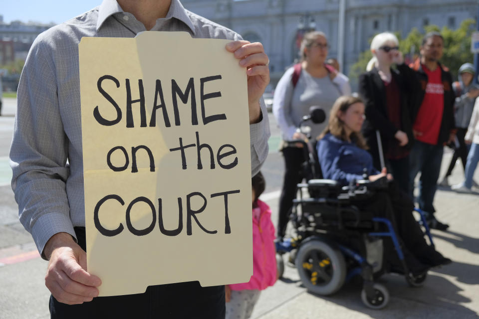 <p>Don Cornejo, of Berkeley, Calif., holds up a sign as people listen to impacted community members speak about the Supreme Court decision on the ban of travel from several mostly Muslim countries during a news conference outside City Hall Tuesday, June 26, 2018, in San Francisco, Calif. (Photo: Eric Risberg/AP) </p>