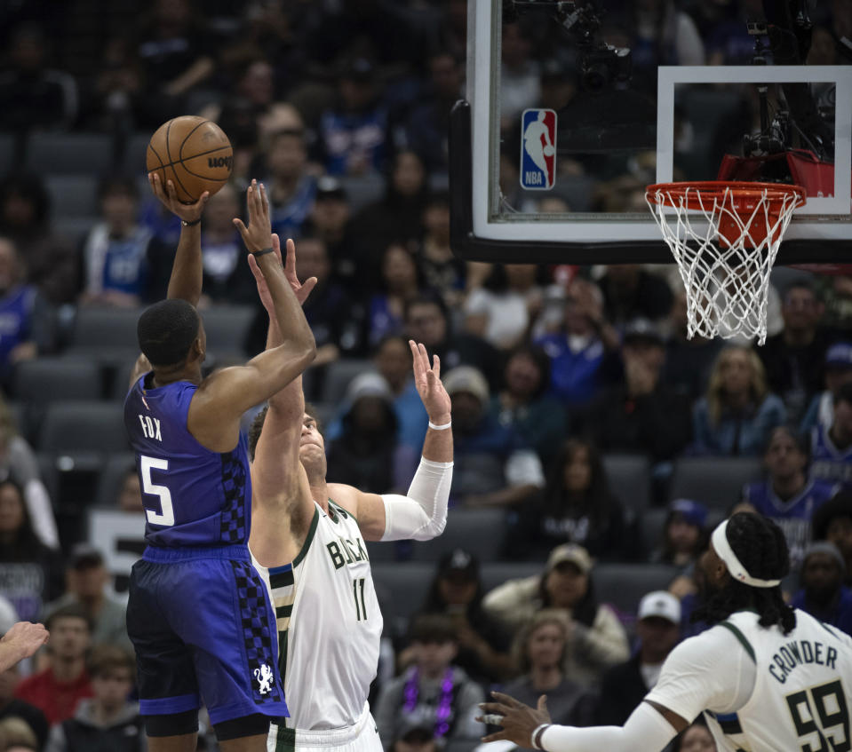 Sacramento Kings guard De'Aaron Fox (5) scores over Milwaukee Bucks center Brook Lopez (11) in the first quarter of an NBA basketball game in Sacramento, Calif., Tuesday, March 12, 2024. (AP Photo/José Luis Villegas)