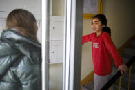 Social worker Rebekka Rauchhaus of the Christian charity the Arche, or Ark, talks with Sara in the entrance of an apartment building in the Hellersdorf suburb of Berlin, Germany, Thursday, April 2, 2020. The group provides help to about 1,300 poor families across Germany, is now delivering food, hygiene products and children's games to family's doorsteps during the coronavirus. (AP Photo/Markus Schreiber)