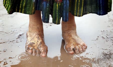 A festival goer stands barefoot in a muddy puddle at Worthy Farm in Somerset, on the third day of the Glastonbury music festival June 27, 2014. REUTERS/Cathal McNaughton