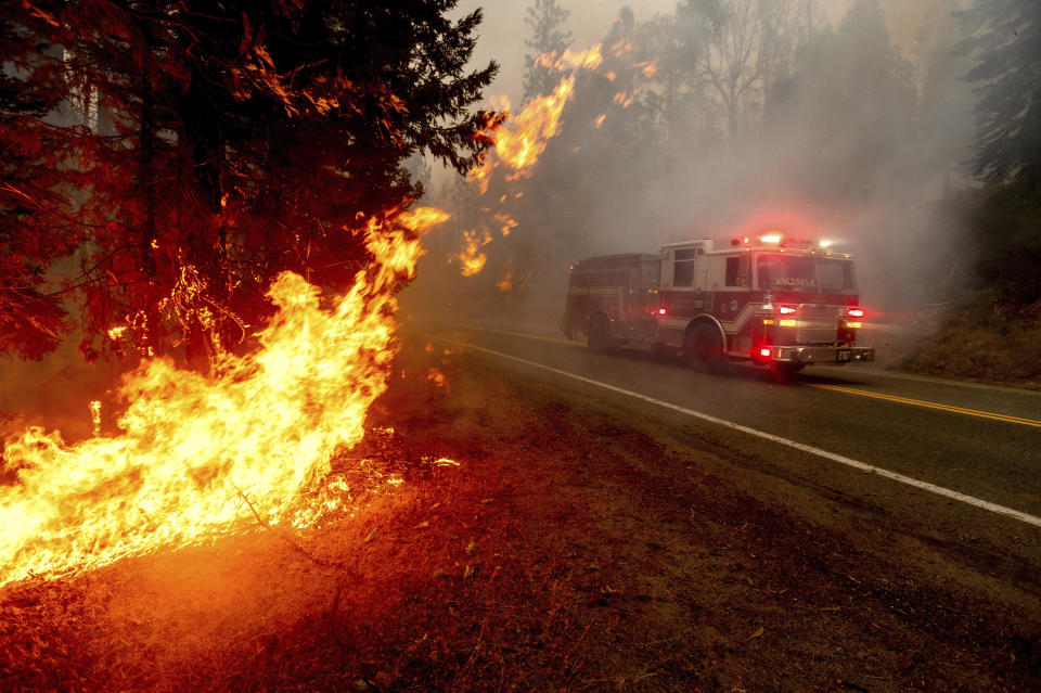 FILE - In this Sept. 7, 2020, file photo a firetruck drives along state Highway 168 while battling the Creek Fire in the Shaver Lake community of Fresno County, Calif. A weekend wildfire east of Fresno exploded so fast that it trapped hundreds of holiday campers who were airlifted to safety in a dramatic rescue that strained the limits of two California National Guard helicopters. (AP Photo/Noah Berger, File)