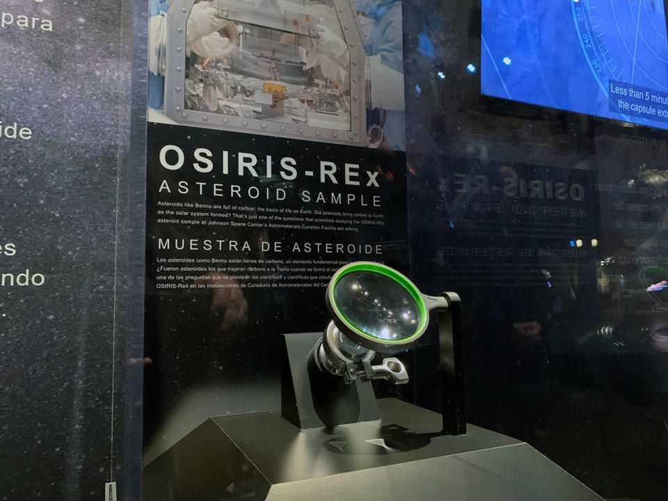 close up of a glass display case in a museum showing a small asteroid sample returned to earth by nasa's osiris-rex mission