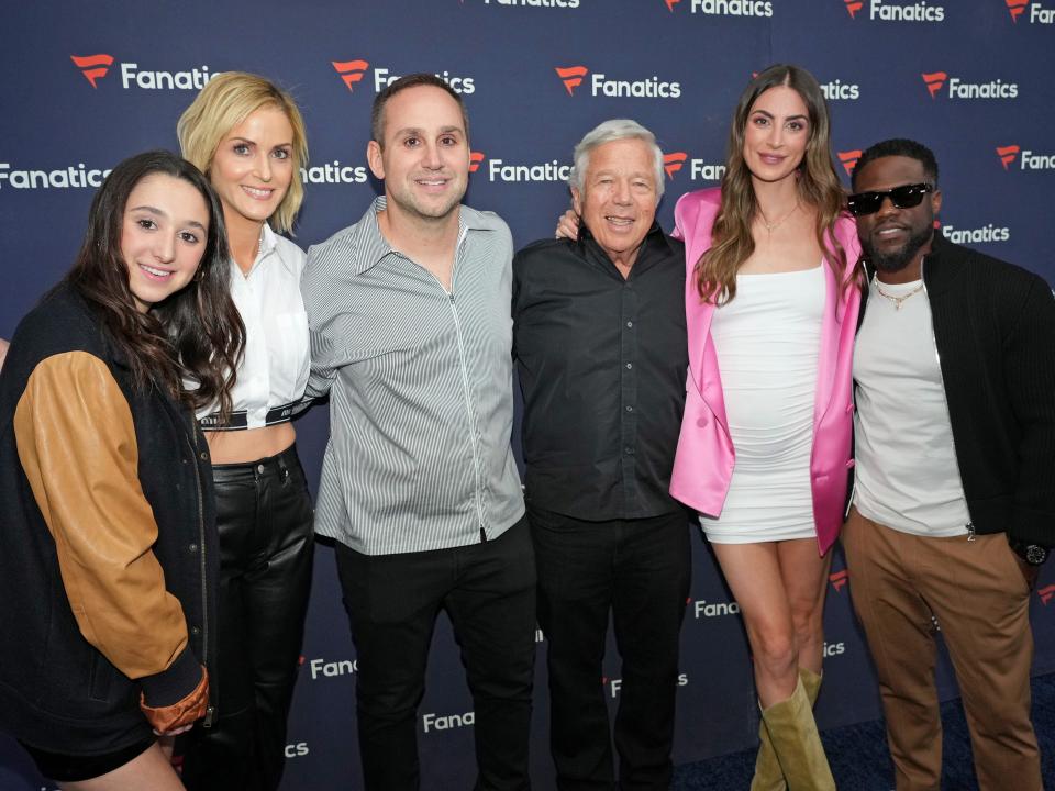 kylie rubin, a teenager, dr. dana blumberg, a middle aged woman, michael rubin, a middle aged man, robert kraft, an older man, camille fishel, a middle-aged woman, and kevin hart, a middle-aged man stand together on a red carpet with their arms around each other