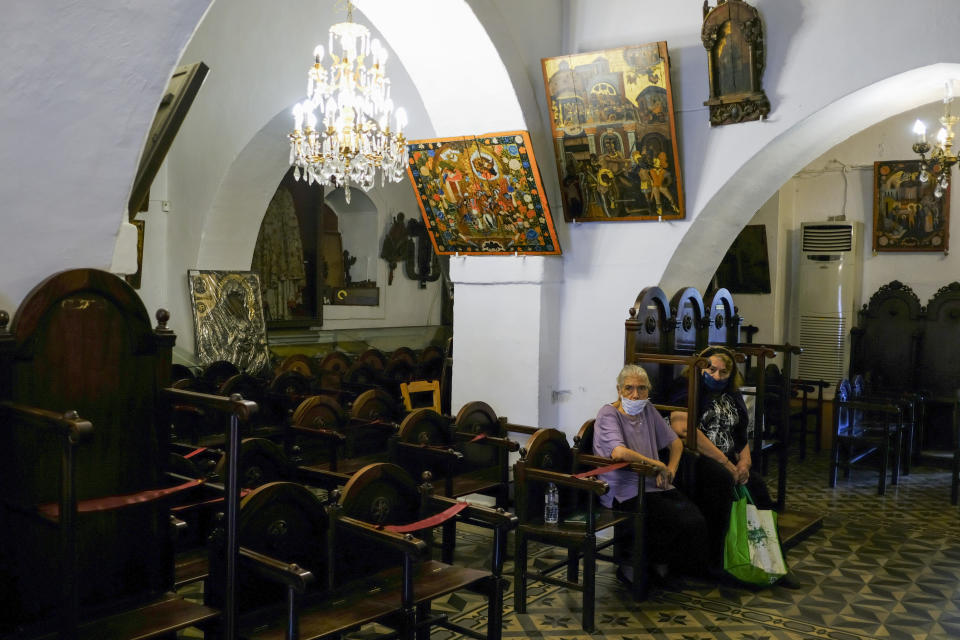 Two women sit inside the Virgin Mary, during a vaccination roll out, in the town of Archanes, on the island of Crete, Greece, Monday, Sept. 6, 2021. Greece has begun administering vaccinations for COVID-19 outside churches. It's a pilot program that was recently announced by the government as a means of encouraging more people to get the shots. Mobile National Health Organization units began administering shots Monday in a church yard in the town of Archanes near the city of Heraklion on the southern island of Crete. (AP Photo/Michael Varaklas)