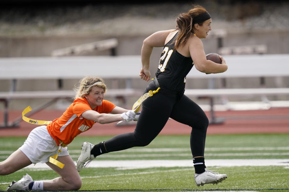 FILE - Ottawa quarterback Madysen Carrera (21) is tackled by Midland defender Casey Thompson, left, during an NAIA flag football game in Ottawa, Kan., Friday, March 26, 2021. Not surprisingly, the NFL is a big part of the push to make flag football an Olympic sport — at least for a one-off in Los Angeles. (AP Photo/Orlin Wagner, File)