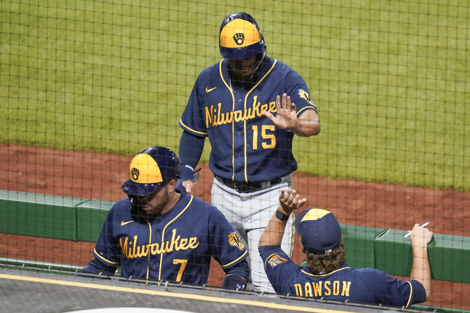 Milwaukee Brewers' Tyrone Taylor (15) and Victor Caratini (7) are greeted by hitting coach Connor Dawson after scoring on a hit by Willy Adames during the eighth inning of the team's baseball game against the Pittsburgh Pirates, Wednesday, Aug. 3, 2022, in Pittsburgh. (AP Photo/Keith Srakocic)