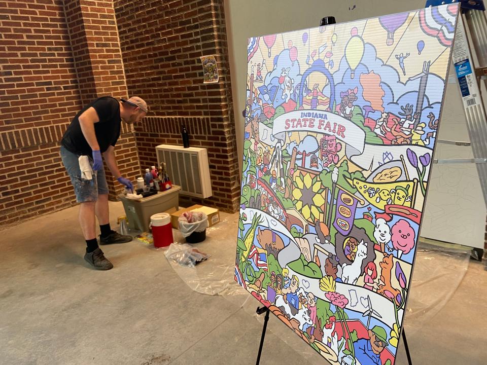 Erik Lundorf inspects his art supplies as he readies to work on a mural at the entrance to the Indiana Farm Bureau Fall Creek Pavilion at the Indiana State Fairgrounds. The facility was unveiled July 20, 2023.