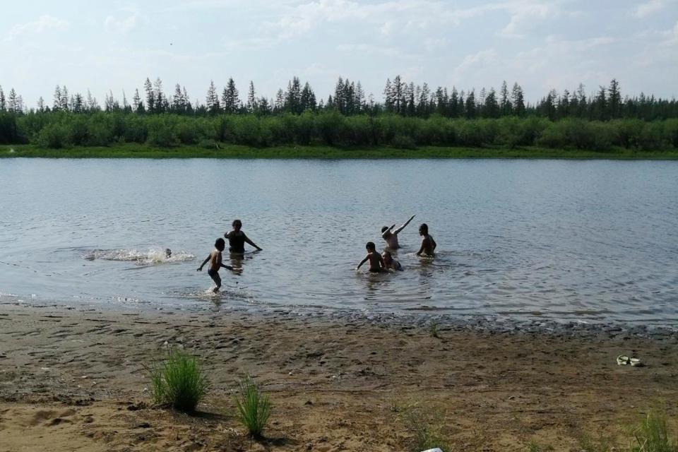 In this handout photo provided by Olga Burtseva, children play in the Krugloe lake outside Verkhoyansk, the Sakha Republic, about 2900 miles northeast of Moscow, Russia, on Sunday, June 21, 2020.