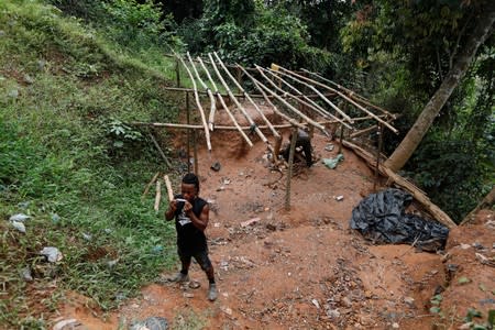 An informal gold miner rolls a cigarette at the site of Nsuaem-Top