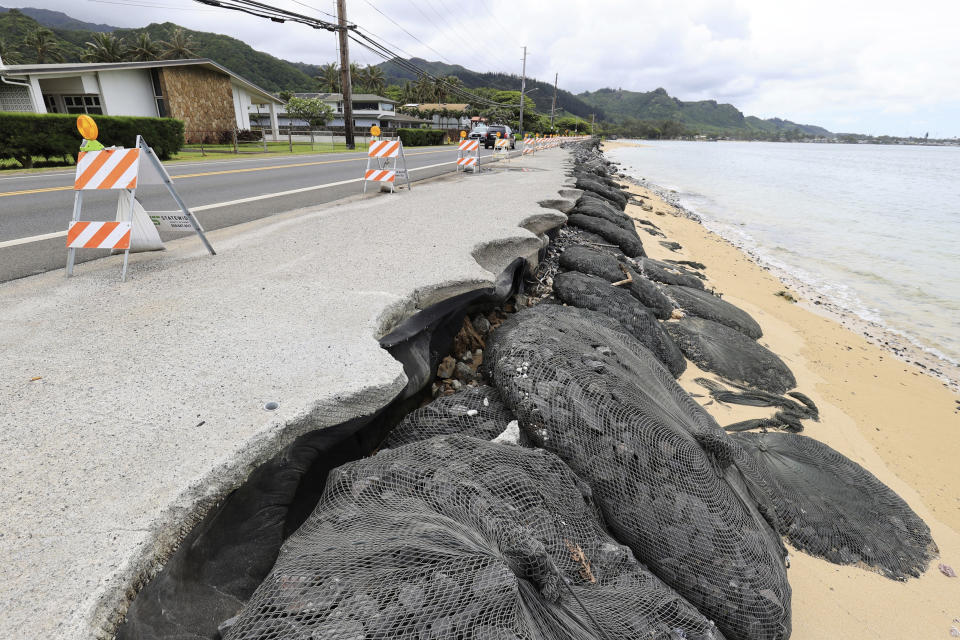 Cars drive down an eroded Kamehameha Highway, Thursday, May 11, 2023, in Hauula, Hawaii. Rising seas are eroding Hawaii's coast near homes with cesspools, pulling sewage out to sea. (AP Photo/Marco Garcia)