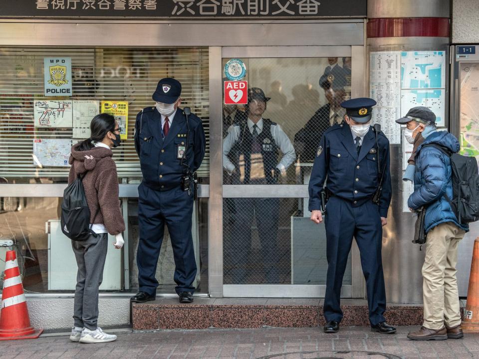 People wearing face masks ask directions from police officers who are also wearing face masks, at a police box by Shibuya crossing on February 27, 2020 in Tokyo, Japan.