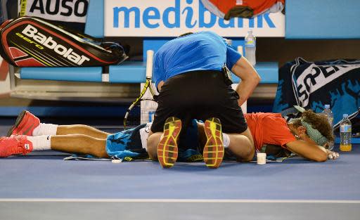 Un entrenador trabajando con la espalda del español Rafael Nadal durante el partido contra el suizo Stanislas Wawrinka, en la final del Abierto de Australia, el 26 de enero de 2014, donde se ha impuesto el segundo por sorpresa en cuatro sets (AFP | Greg Wood)