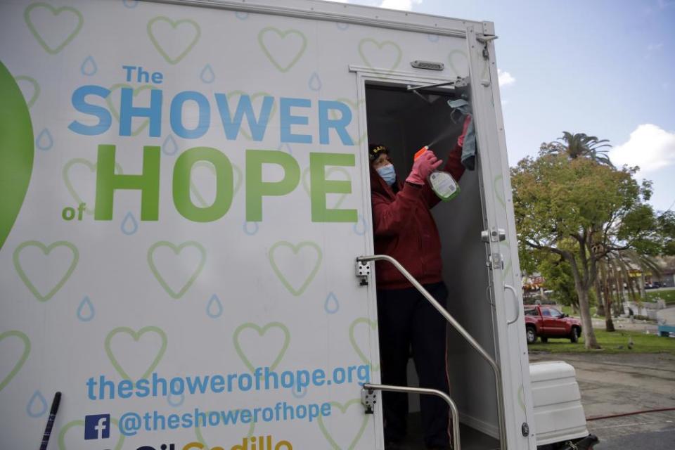 Lisa Marie Nava cleans a mobile shower provided by the Shower of Hope, a homeless services group, in MacArthur Park in Los Angeles on 23 March 2020.