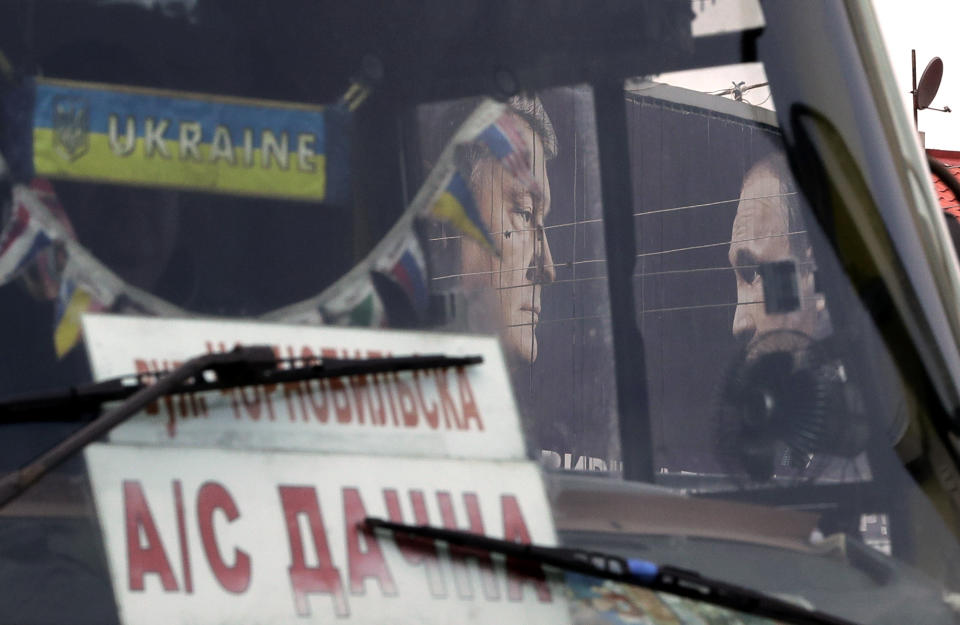 A bus drives past a billboard depicting Ukraine's President Petro Poroshenko and Russian President Vladimir Putin looking at each other in Kiev, Ukraine, Wednesday, April 17, 2019. The second round of presidential vote in Ukraine will take place on April 21. (AP Photo/Sergei Grits)