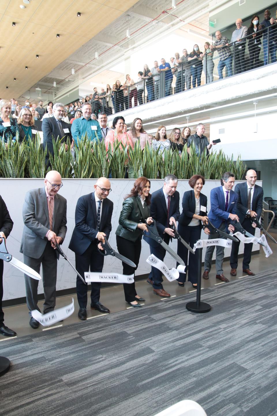 Gov. Gretchen Whitmer, Wacker Chemical Corp. president and CEO David Wilhoit, both center, and several other Wacker executives and other dignitaries cut the ribbon at Wacker's new Innovation Center just outside Ann Arbor during a ceremony Tuesday. The ceremony took place before Wacker employees in the facility's "collaboration spine."