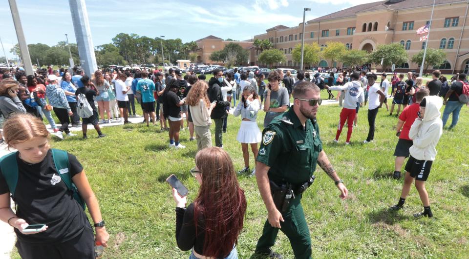 Mainland High School students check their phones while waiting for law enforcement to clear the building on Friday, Sept. 9, after a security staffer used their panic button. The rumor of a gun was unfounded.