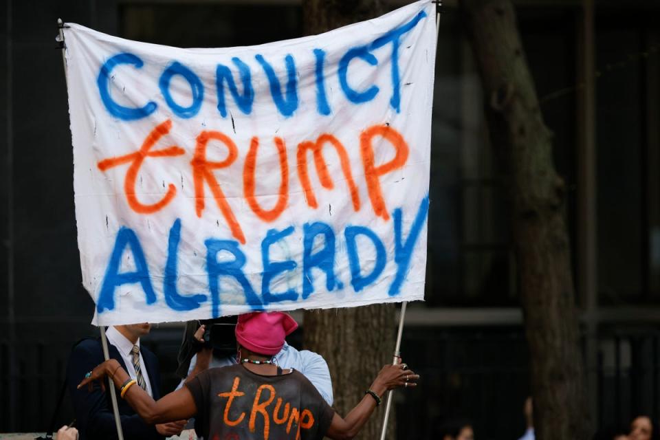 Protestor holds up a sign that reads ‘Convict Trump Already’ (AP)