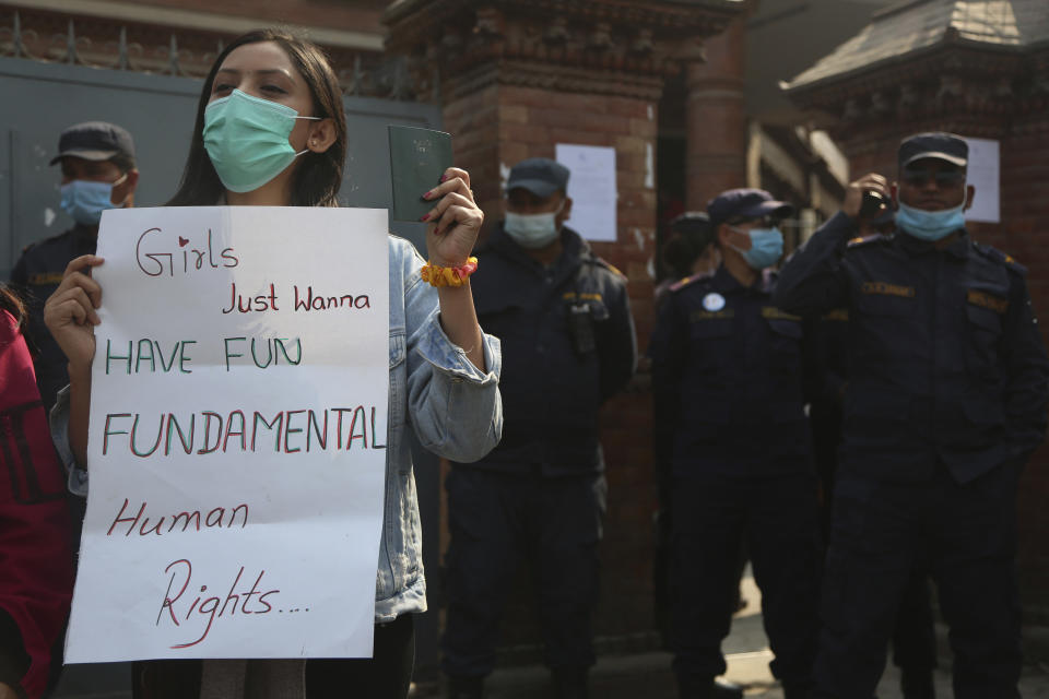 A Nepalese woman holds a placard against a proposed rule which restricts foreign travel for women under 40 years during a protest outside the Department of Immigration in Kathmandu, Nepal, Thursday, Feb.11, 2021. Nepal government is proposing a new rule that says women under 40 years of age must seek consent from the family–and even the concerned ward office–to travel abroad on a visit visa. (AP Photo/Niranjan Shrestha)